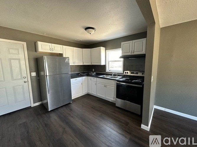 A kitchen with a refrigerator, stove, and cabinets.