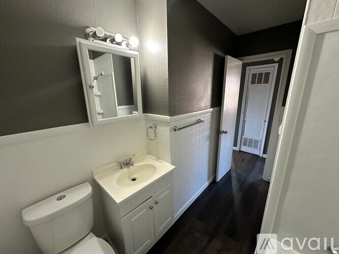 A bathroom with a toilet, sink, and mirror.