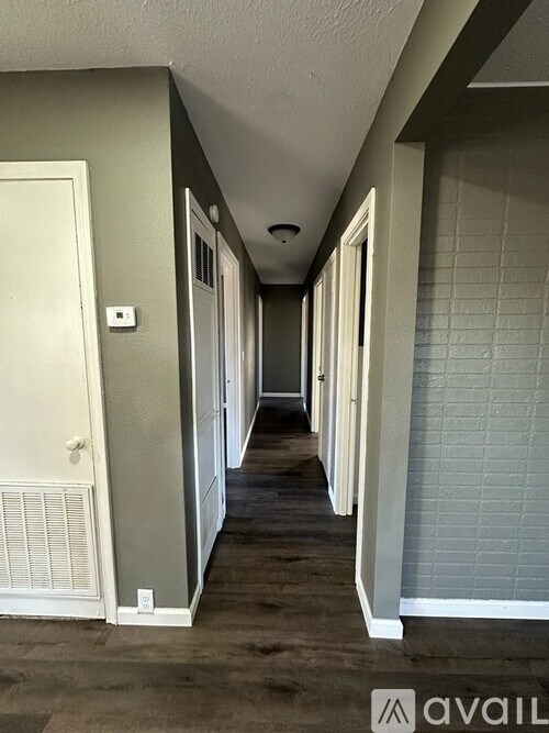A long hallway with white doors and a brick wall.