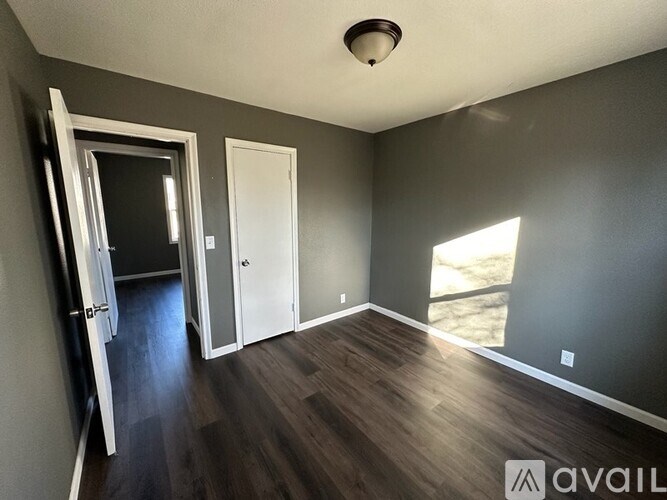 A room with a wooden floor and a window letting in sunlight.