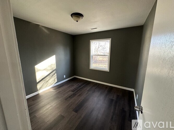 A room with a window and wooden flooring.