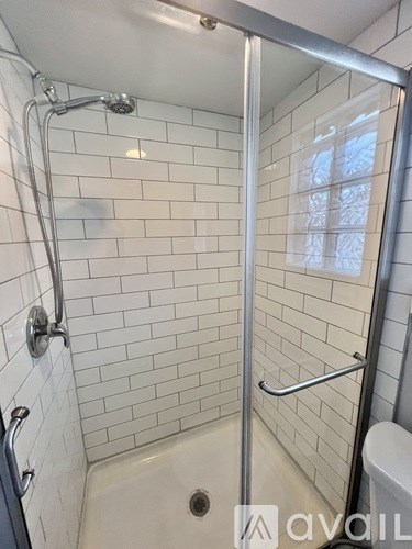 A shower with a glass door and a chrome shower head.
