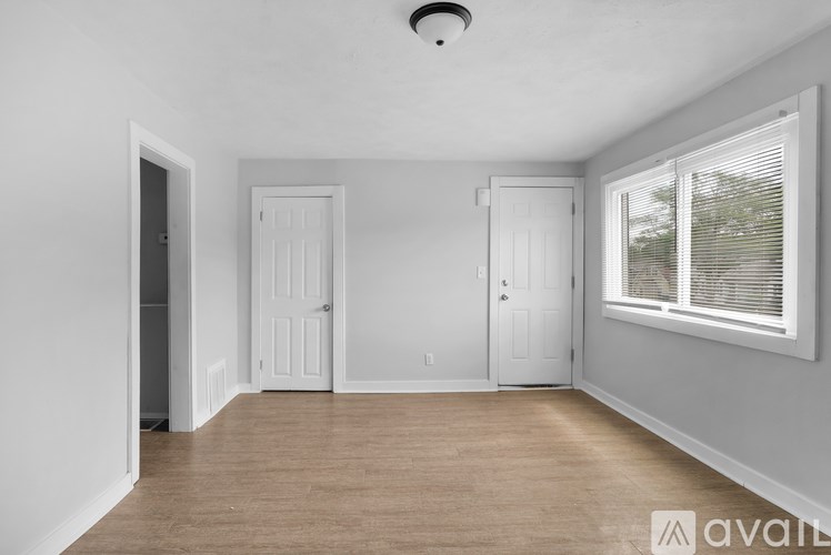 A room with two doors and a window with blinds.