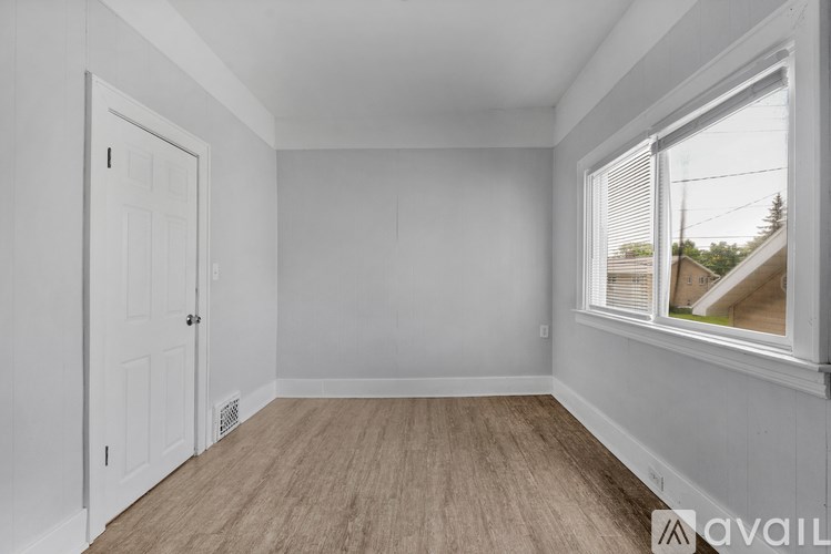 A room with a door, window, and wooden floor.