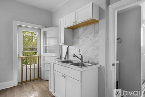 A kitchen with white cabinets and a marble backsplash.