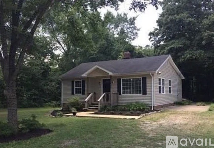 A small house with a porch and a tree in front.