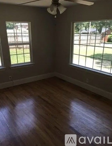 A room with wooden floors and two windows.