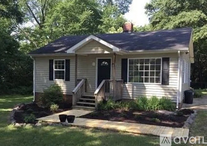 A small house with a front porch and a black door.