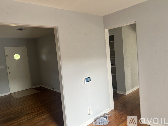 A room with a white door and a white wall with a small window.