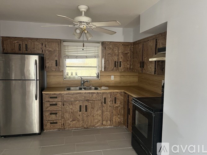 A kitchen with wooden cabinets and a stainless steel refrigerator.