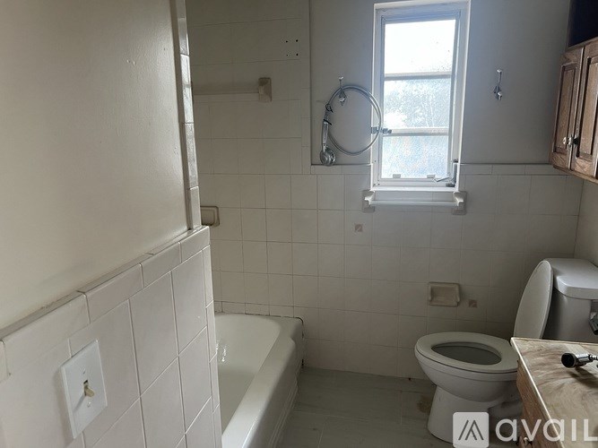 A white bathroom with a toilet, tub, and window.