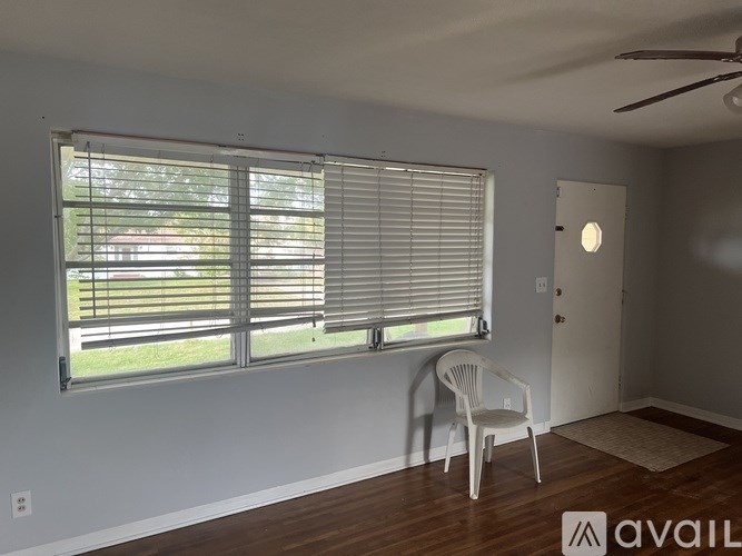 A room with a chair and a window with blinds.