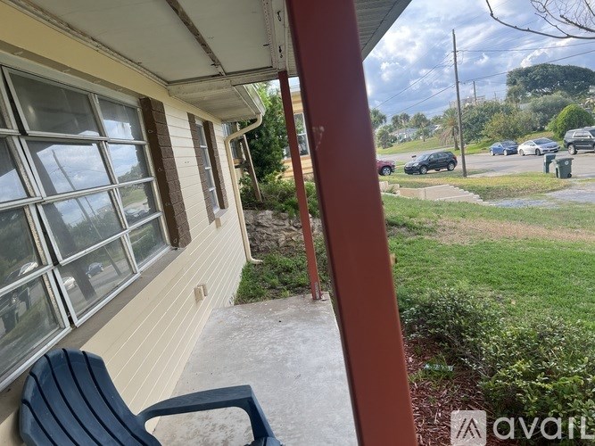 A view from a house looking out to a street with cars and trees.