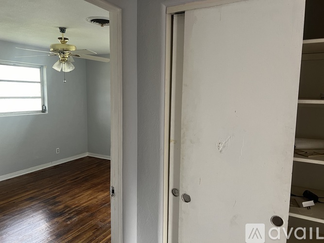 A room with a ceiling fan and wooden floors.