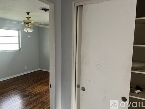 A room with a ceiling fan and wooden floors.