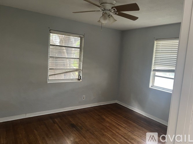 A room with a ceiling fan and two windows.