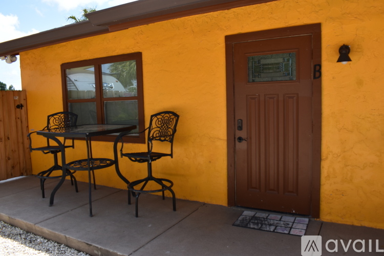 A yellow house with a brown door and a table and chairs on the patio.
