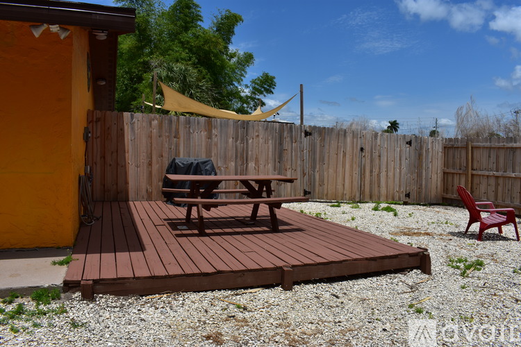 A wooden deck with a picnic table and a red chair.