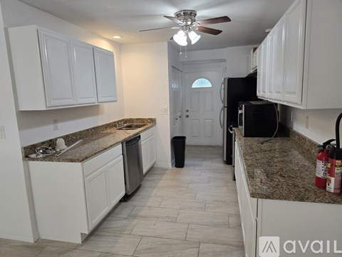 A kitchen with white cabinets and granite countertops.