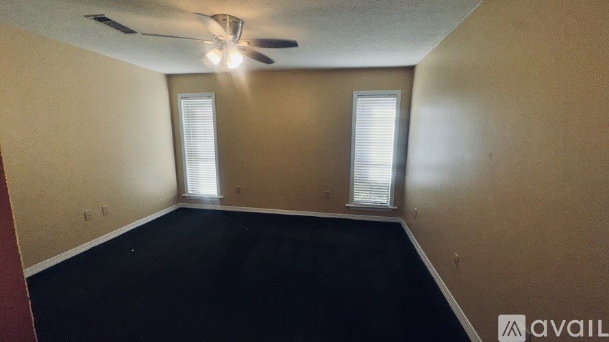 A room with a ceiling fan and two windows.