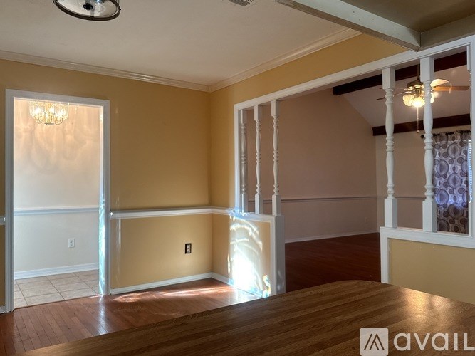 A room with a wooden floor and a chandelier hanging from the ceiling.