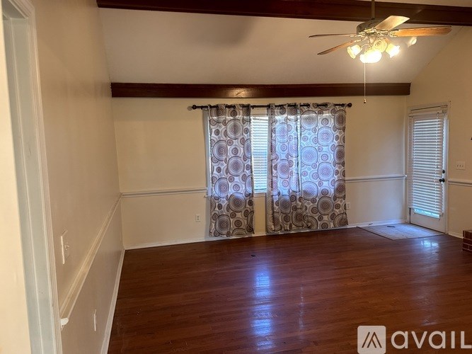 A room with a ceiling fan and patterned curtains.