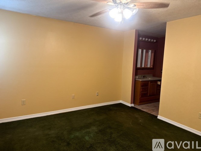 A room with a ceiling fan and a green carpet.