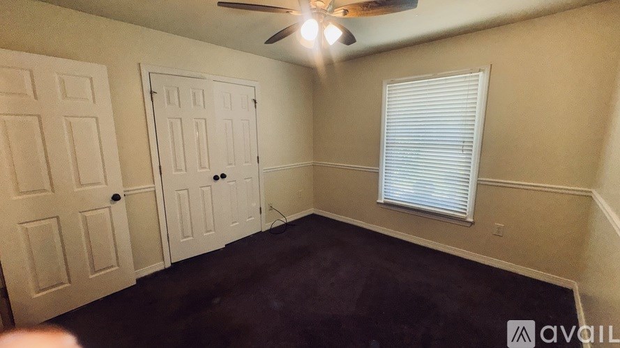 A room with a ceiling fan and a window with blinds.