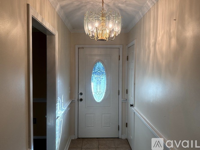 A hallway with a chandelier and a door with a stained glass window.