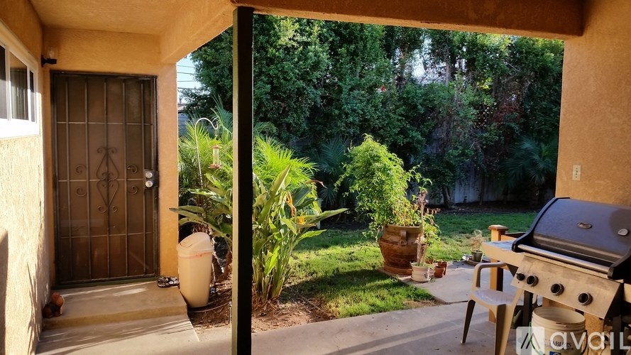 A patio with a grill and a view of a backyard.