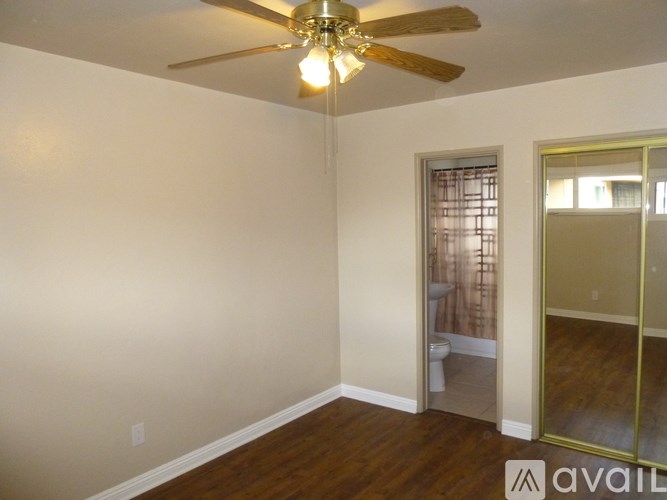 A room with a ceiling fan and a door leading to a bathroom.