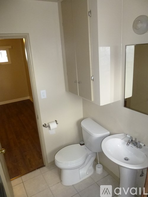 A bathroom with a toilet, sink and mirror.