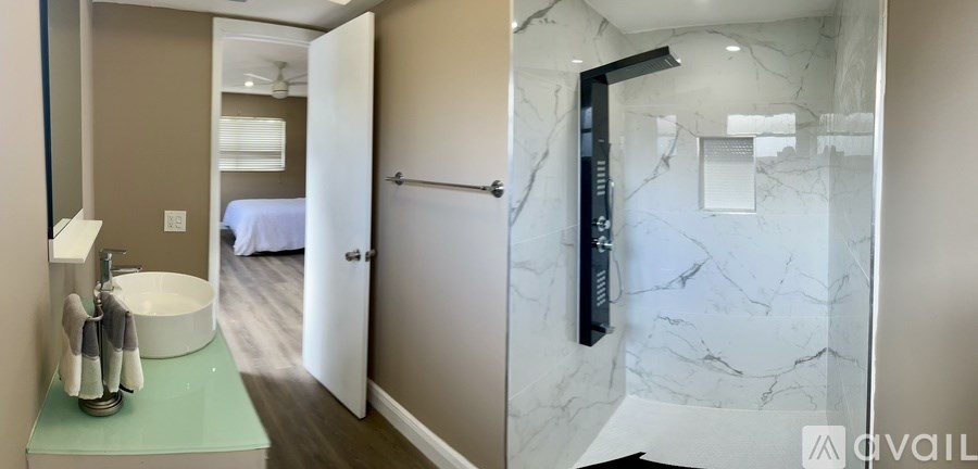 A bathroom with a marble shower and a white sink.