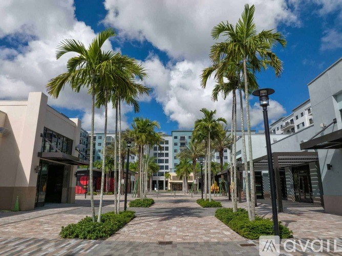 A sunny day at the plaza with palm trees and modern buildings.