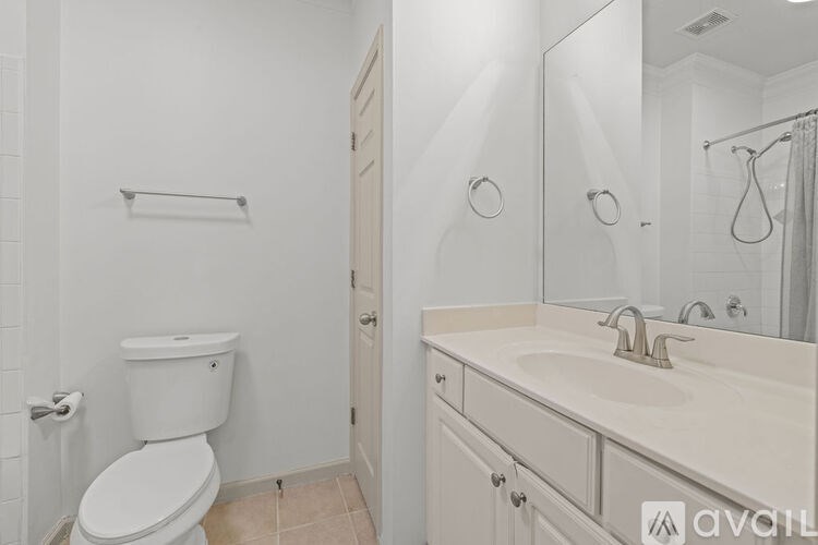 A white bathroom with a toilet, sink, and mirror.