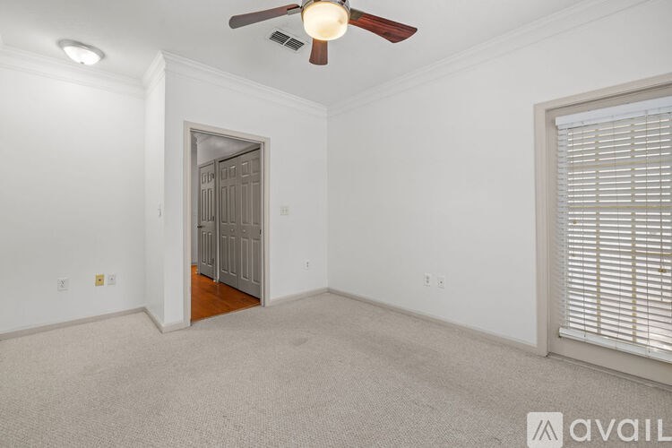 A room with a ceiling fan and a door leading to another room.