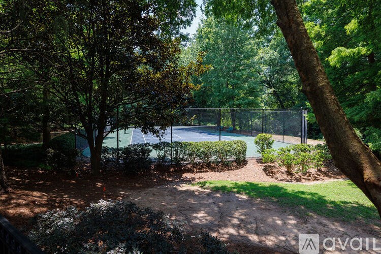 Tennis court surrounded by trees and bushes.