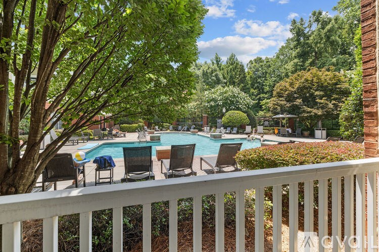 A pool surrounded by trees and chairs.