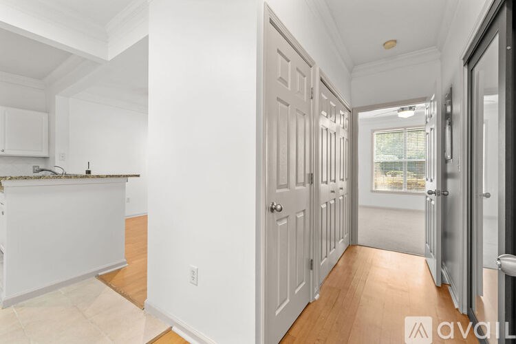A hallway with a white door and a window in the background.