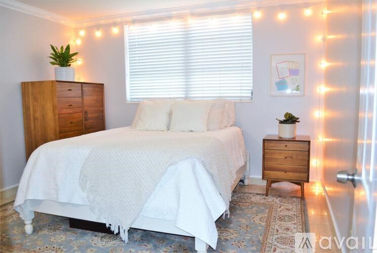 A bedroom with a bed, nightstand, and a wall of lights.