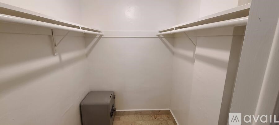 A small, empty closet with a shelf and a trash can.
