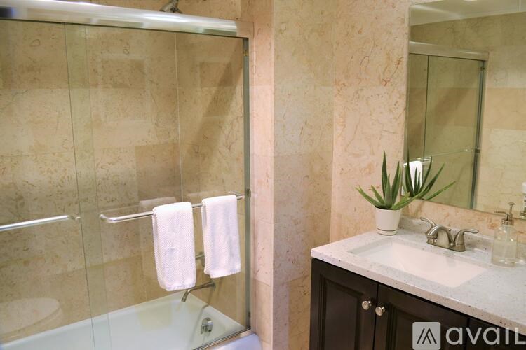 A bathroom with a glass shower door, a sink, and a mirror.
