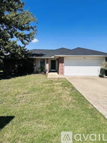 A house with a white garage door and a tree in front.