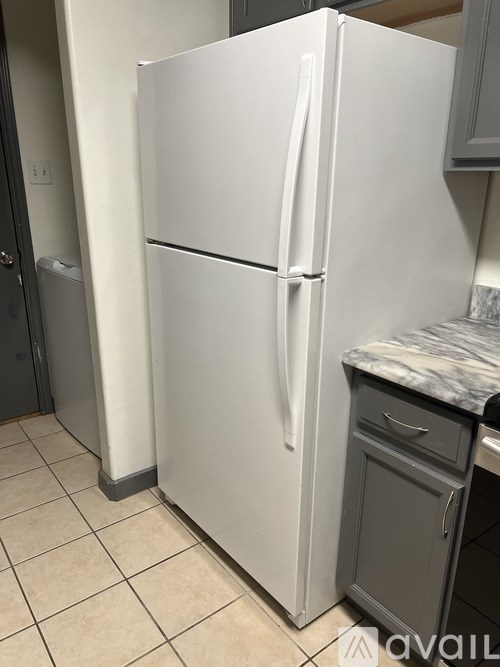 A white refrigerator in a kitchen with a marble countertop.