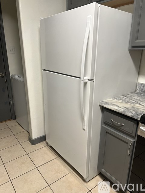 A white refrigerator in a kitchen with a marble countertop.