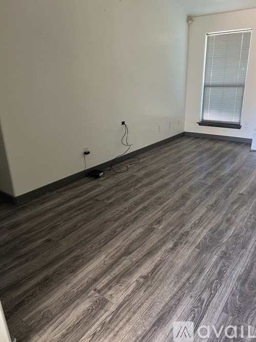 A room with wooden flooring and a window with blinds.