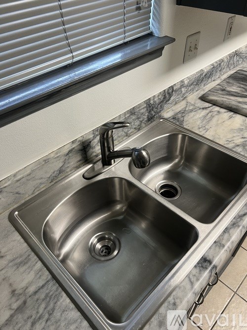 A double sink in a marble countertop with a silver faucet.