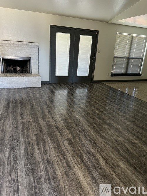 A room with a fireplace and wood flooring.