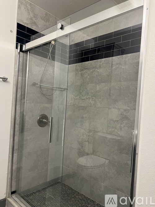 A shower stall with a glass door and a silver handle.