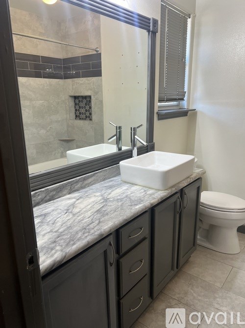 A bathroom with a marble countertop and a toilet.